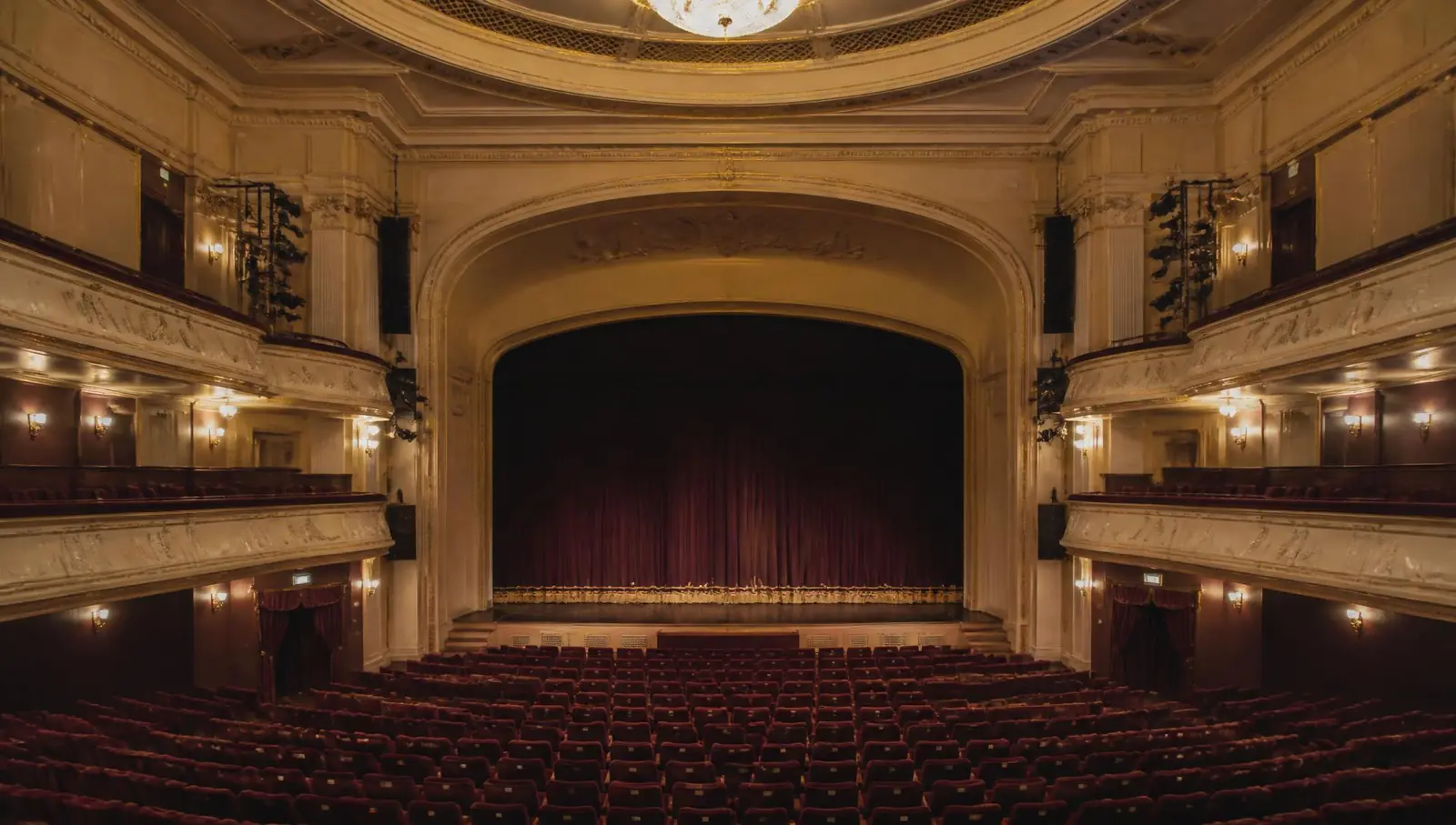 An empty theatre interior glowing in warm light before a company cultural evening